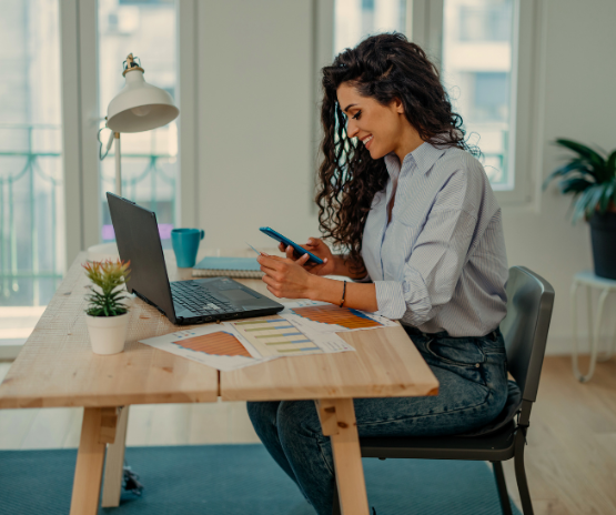 Lady on her phone while sitting at her computer