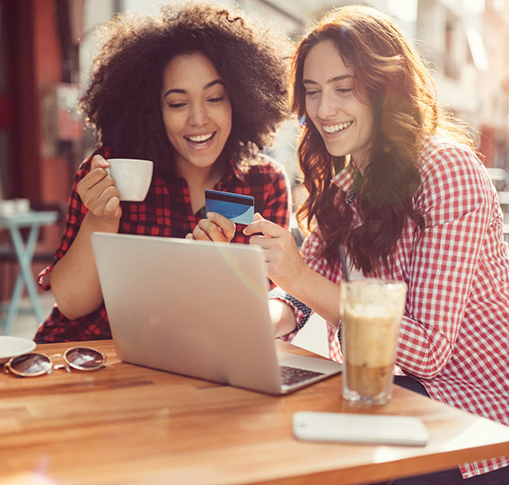 Two young women shopping online with debit card