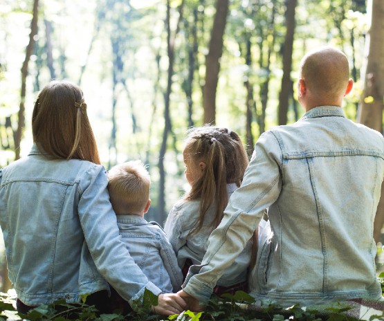 Family poses with their backs towards the camera facing a forest