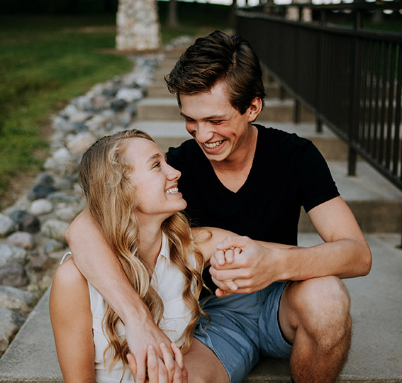 Happy young couple sitting on sidewalk